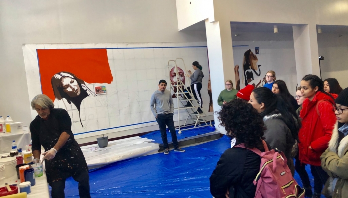 Letelier working on the mural with students.